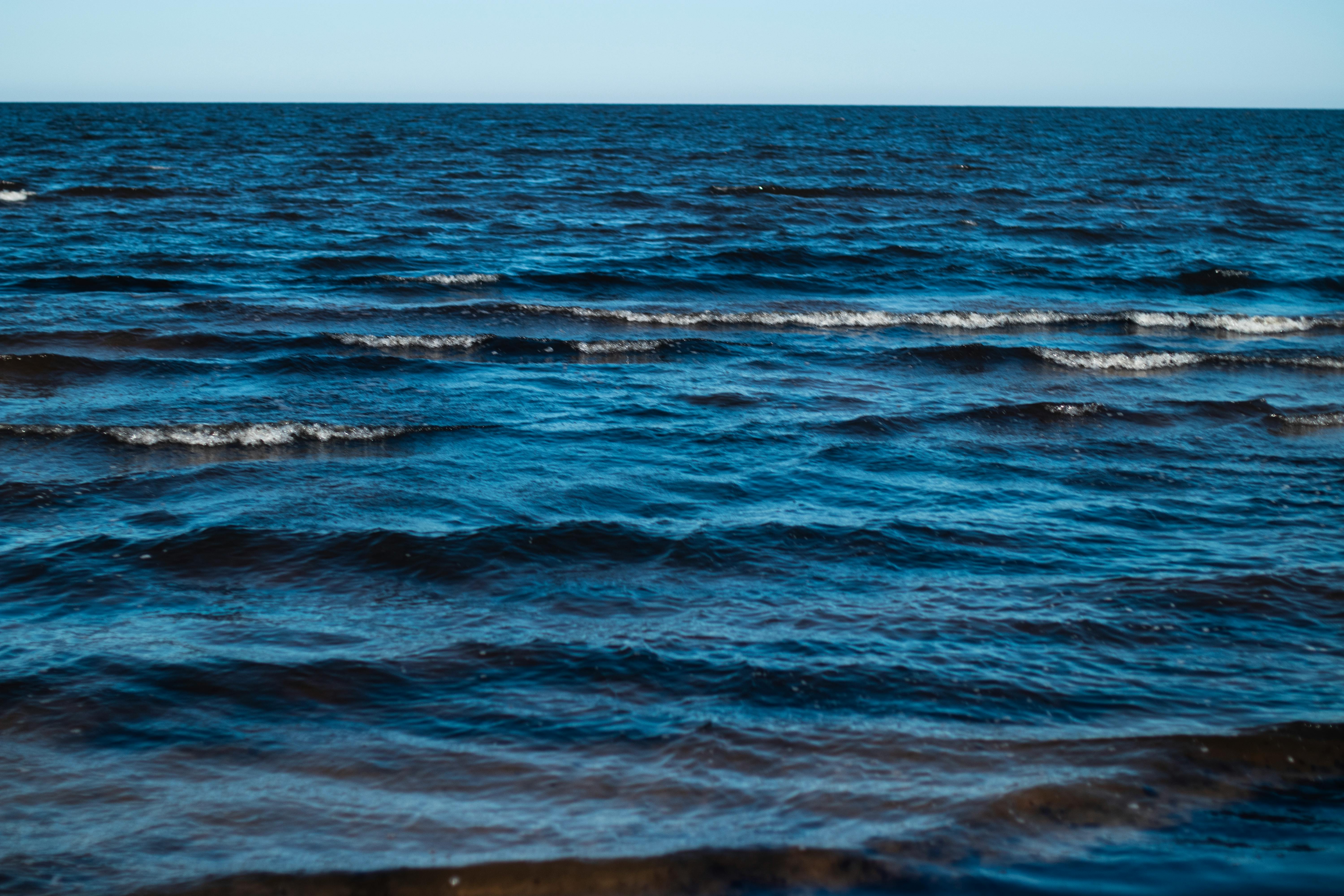 Serene view of gentle blue ocean waves rippling under a clear, cloudless sky.